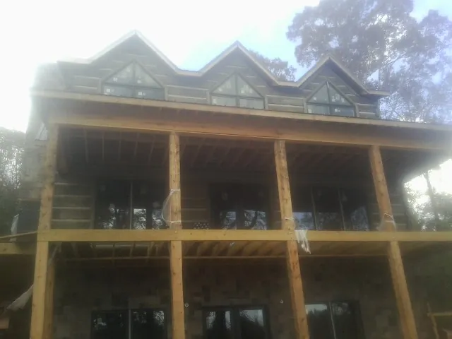 Dormers and porch framing on a large log home under construction — Roof Coating work by our crew in Columbus