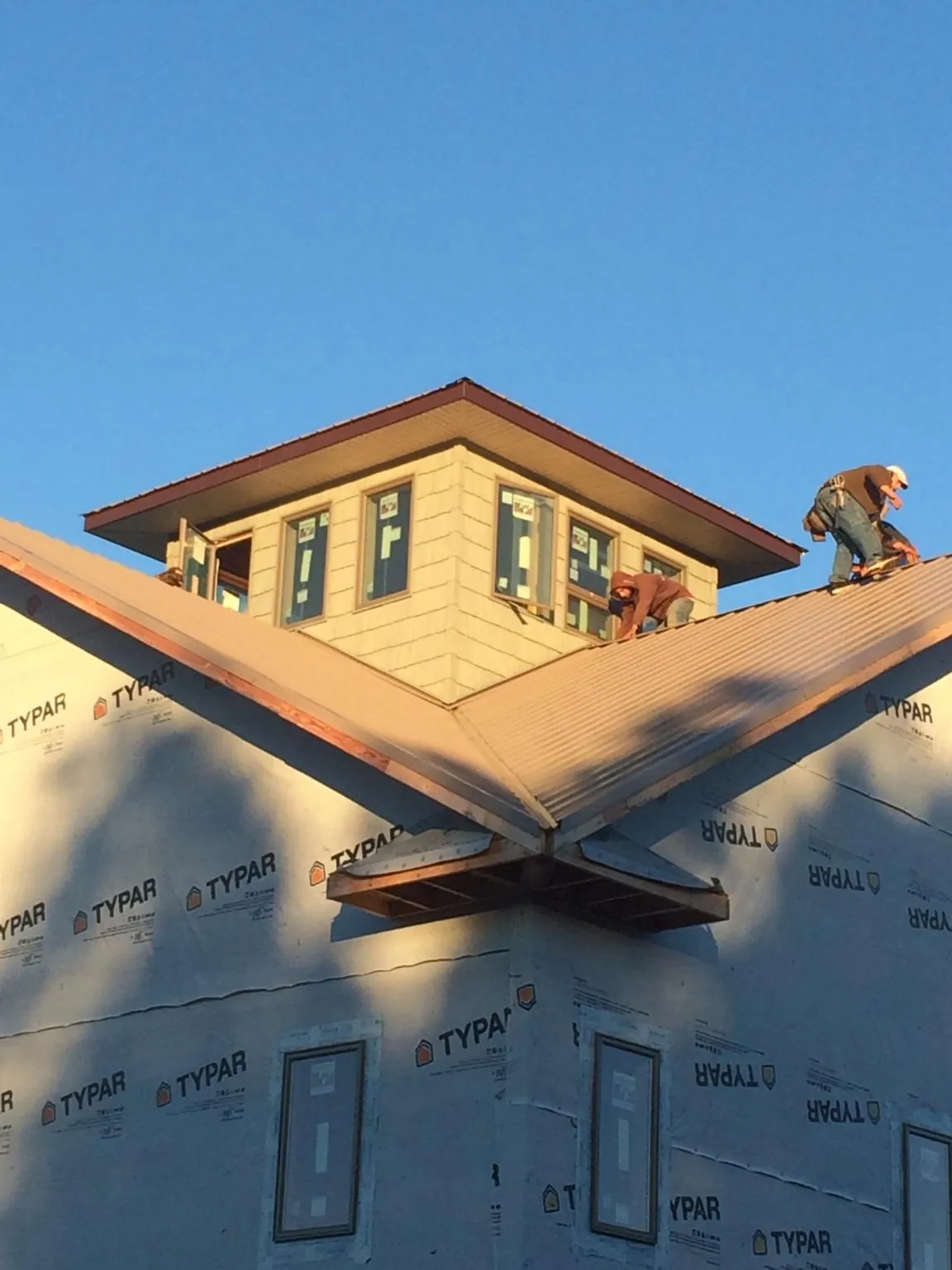 Roofers working around a rooftop cupola on a new metal roof at sunset — Roof Waterproofing in Columbus by Roofing Brothers